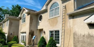 Professional gently soft washing a stucco home on Long Island