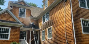 Professional soft washing crew cleaning a Long Island colonial home exterior with low-pressure equipment