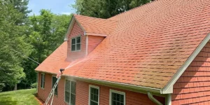Soft wash roof cleaning on a Long Island home with low-pressure spray removing algae and moss