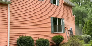 Professional technician soft washing home siding with eco-friendly cleaning solution