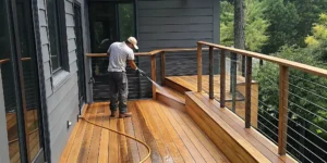 Professional exterior cleaner applying protective oil to a cedar deck on a coastal Long Island property in autumn