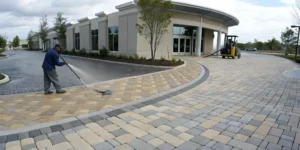 A contractor pressure washing a paver patio before providing a quote for paver sealing.